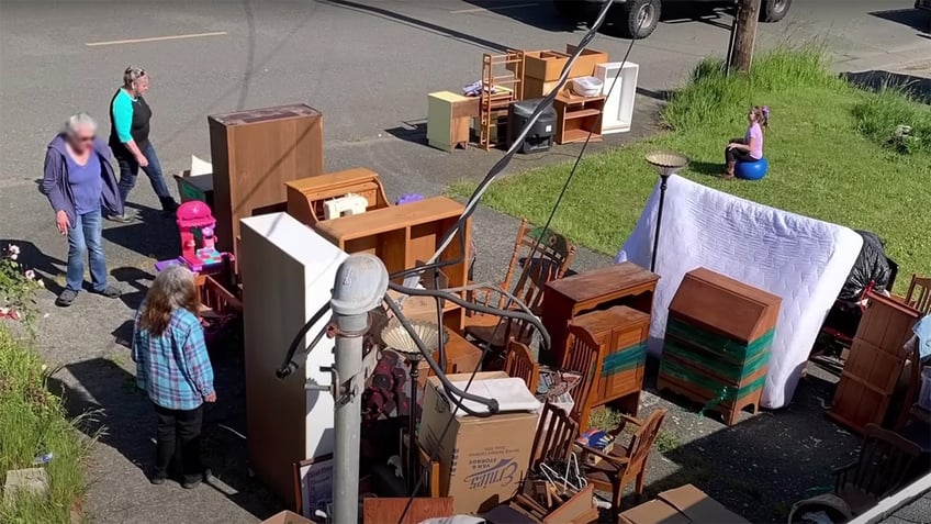 Accused squatters stand in a Northern California driveway near furniture and other belongings