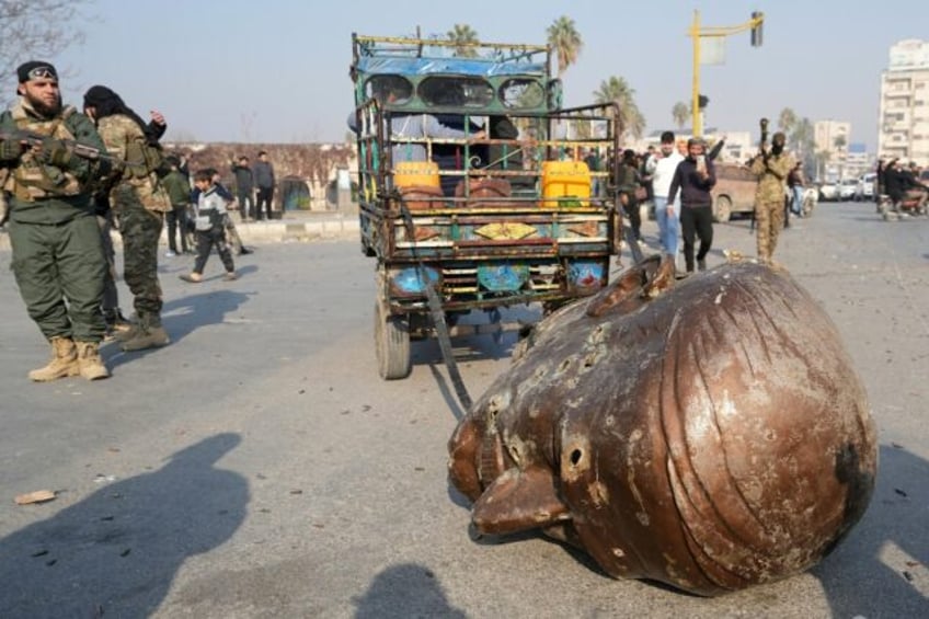 A truck pulls the head from the toppled statue of late Syrian president Hafez al-Assad thr