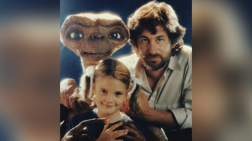 E.T. with Steve Spielberg in a vertical striped shirt and Drew Barrymore with pigtails