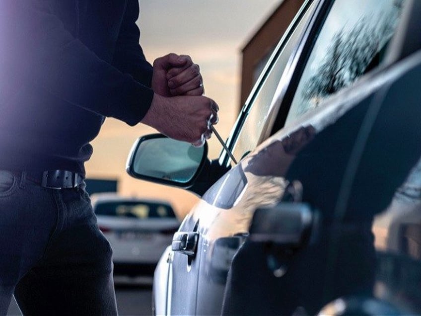 Auto thief trying to break into car - stock photo