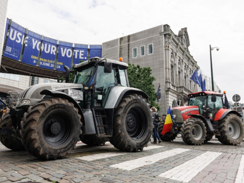 This photograph shows parked tractors in front of a giant poster announcing the upcoming E