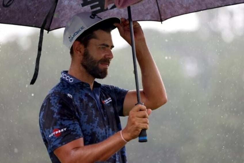 South African Erik van Rooyen stands under an umbrella during a Wednesday practice at the