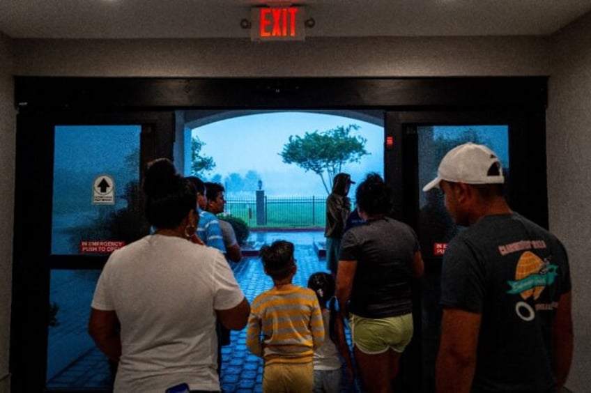 Families watch Hurricane Francine from the entrance of their hotel on September 11, 2024 i