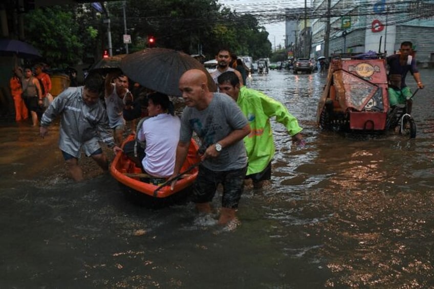 People making their way through a flooded street in Manila as Typhoon Gaemi hit