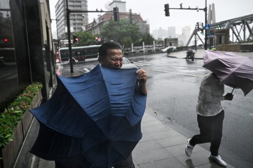 Pedestrians struggle with their umbrellas in strong winds and rain from the passage of Typ