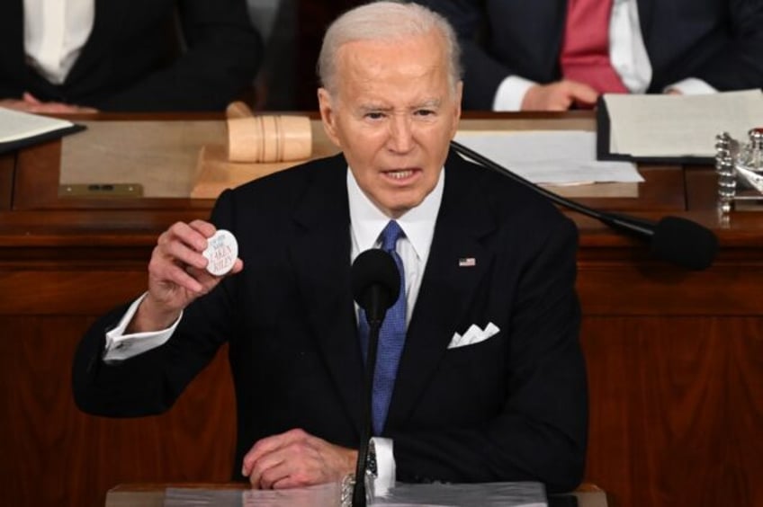 President Joe Biden holds a button that reads 'Say her name: Laken Riley,' during his Stat