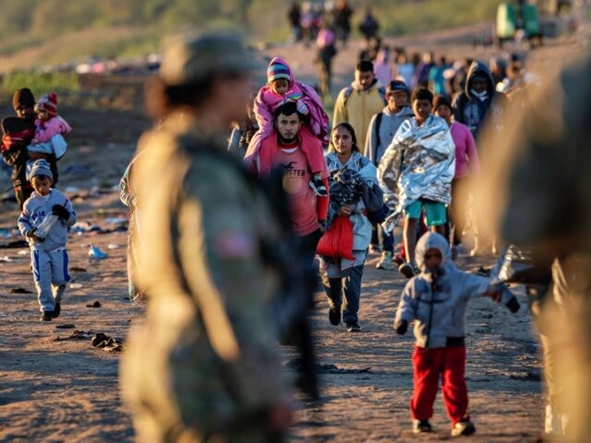 EAGLE PASS, TEXAS - DECEMBER 19: Texas National Guard soldiers observe as thousands of immigrants walk towards a U.S. Border Patrol transit center on December 19, 2023 in Eagle Pass, Texas. Most had crossed the border from Mexico the night before. A major surge of migrants illegally crossing the Rio …