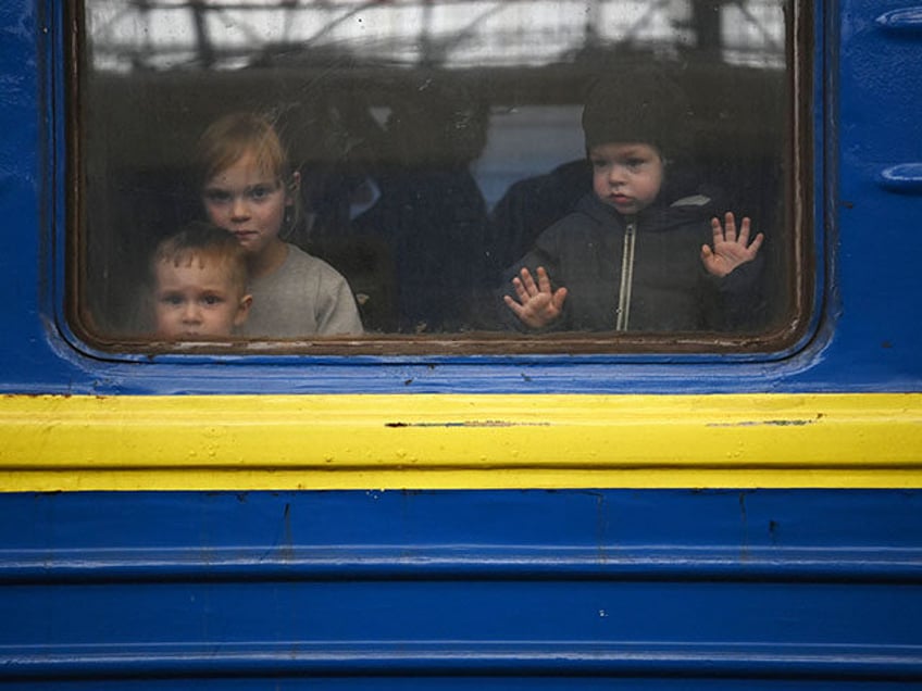 Children look out from a carriage window as a train prepares to depart from a station in L