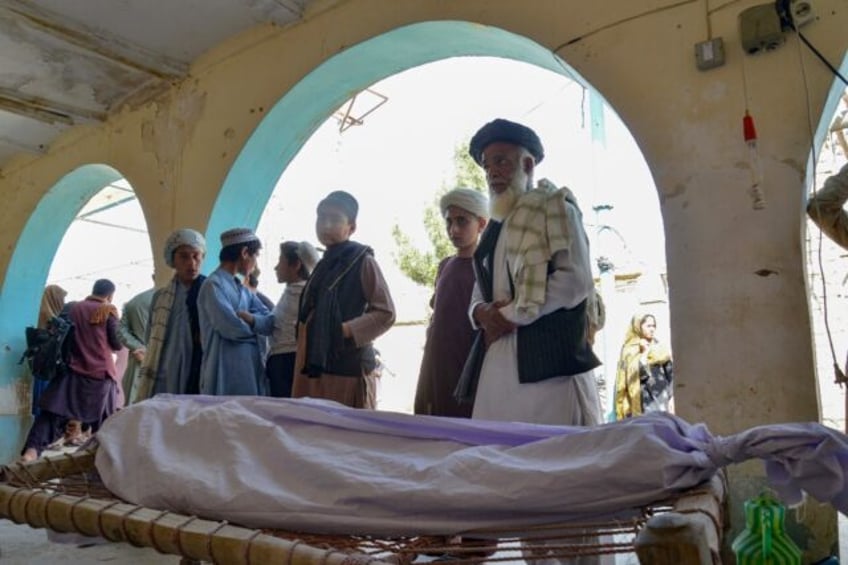 Relatives stand around the dead body of a victim of a suicide bomb attack during a funeral