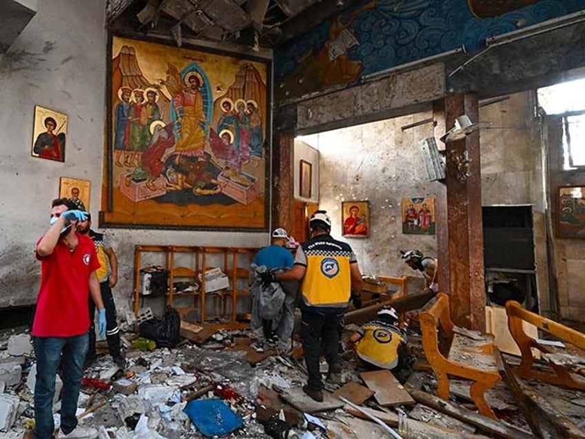 People and rescuers inspect the damage at the site of a reported suicide attack at the Sai