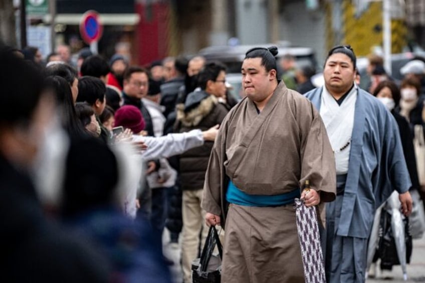 People gather at the entrance of Tokyo's Kokugikan arena for the arrival of sumo wrestlers