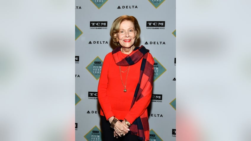 Nancy Olson Livingston wearing a red sweater with a red plaid scarf.