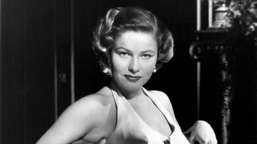 A close-up of Nancy Olson Livingston wearing a white halter dress posing for a glamorous photo.