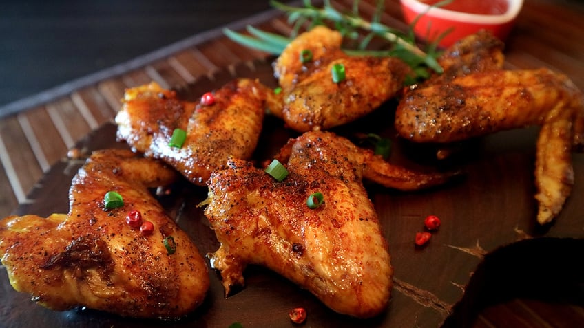 Roasted chicken wings on a piece of wood.