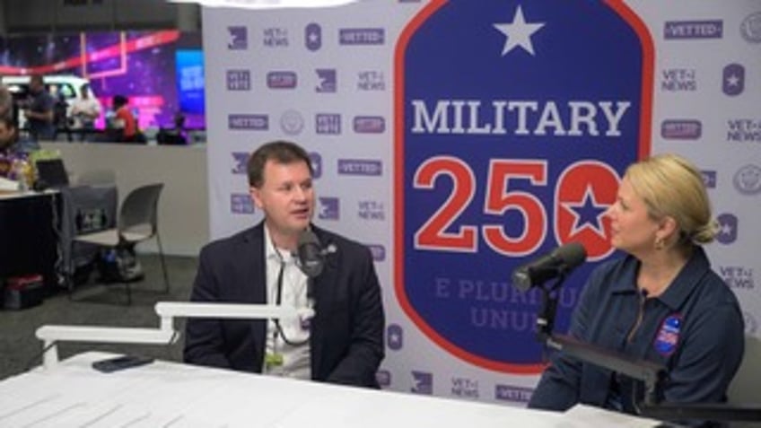 Co-Founder and Executive Director of We the Veterans and Military Families Ellen Gustafson with the LA Secretary of Veterans Affairs USAF Col. (Ret.) Charlton J. Meginley sit in front of a sign celebrating Military250.