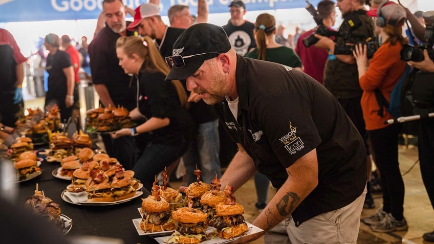 A cook holds a plate of burgers to be judged at the 2023 World Food Championships.