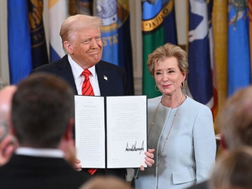 U.S. President Donald Trump holding up a signed executive order poses with U.S. Education