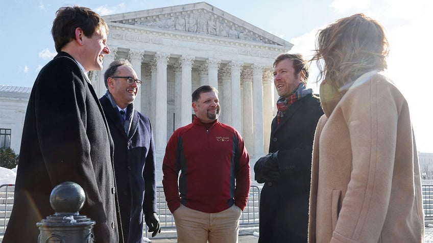 Brandon Trosclair, who owns grocery stores in Louisiana and Mississppi, poses for photos with his legal representatives before the U.S. Supreme Court hears arguments on his case against the Biden administration's nationwide vaccine-or-test-and-mask COVID-19 mandates, in Washington, Jan. 7, 2022. 