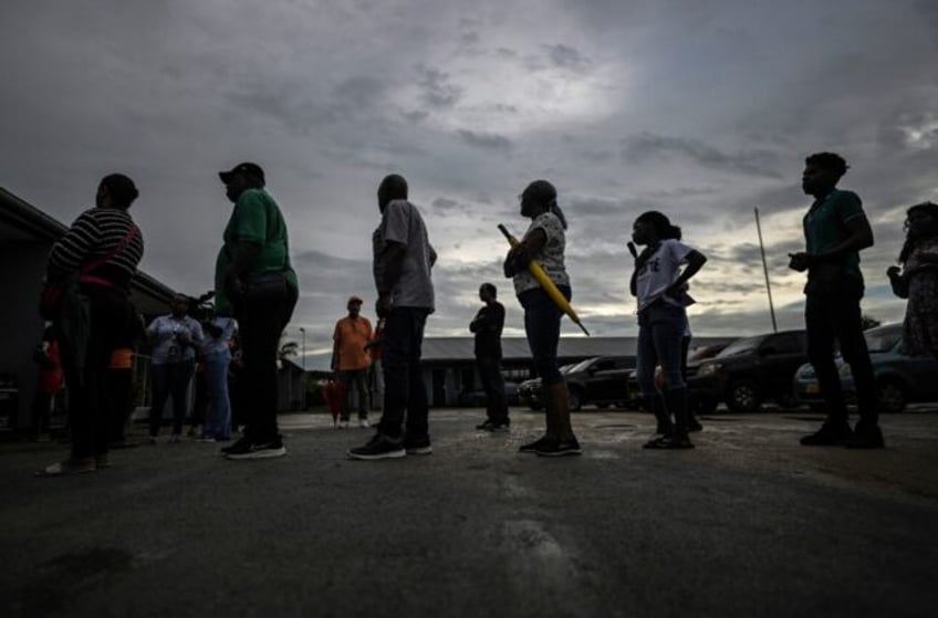 People queue before voting at a polling station during parliamentary elections in Paramari
