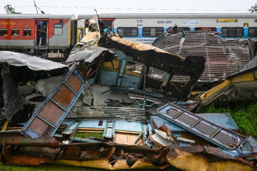 A train drives past the wreckage of another train crash in India's West Bengal state on Ju