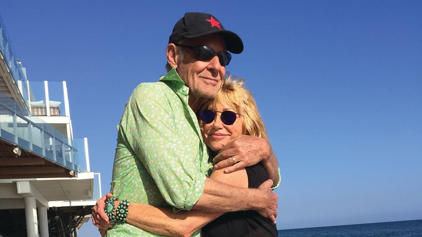 Alan Hamel embracing Suzanne Somers on the beach.