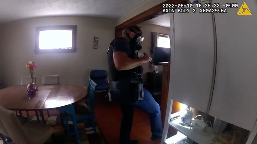 Police officer wearing gas mask searches house