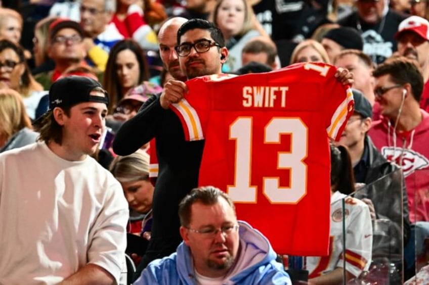 A fan holds up a Kansas City Chiefs jersey with Swift #13 during Super Bowl LVIII Opening