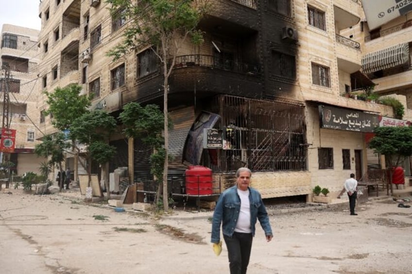 A man walks past a partially burnt building following sectarian clashes in Ashrafiyat Sahn