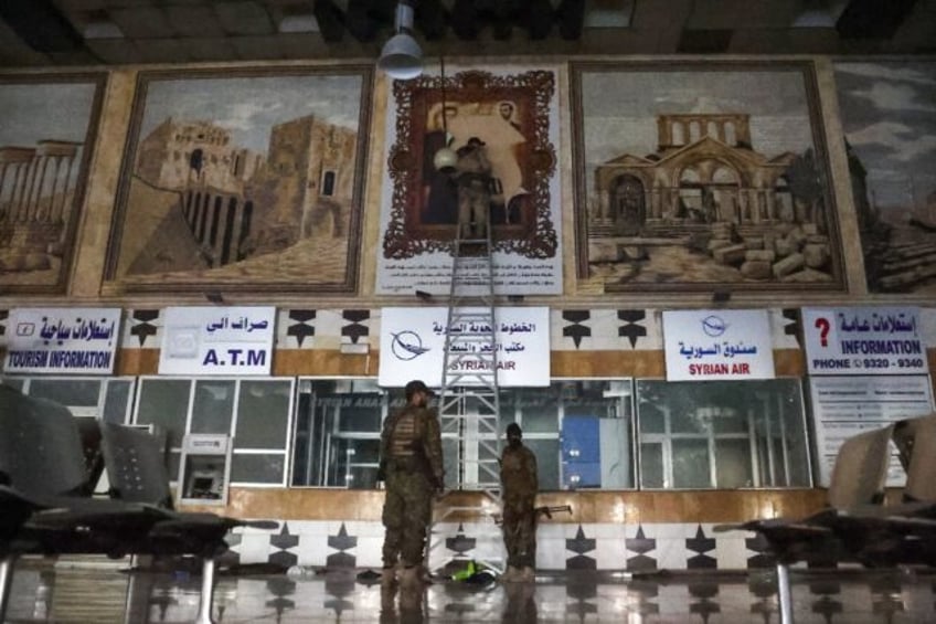 Anti-regime fighters tear off a poster depicting Syrian President Bachar al-Assad and his