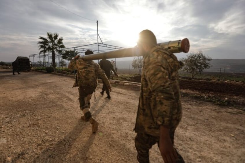 Anti-government fighters carry a rocket in the outskirts of Syria's central city of Hama