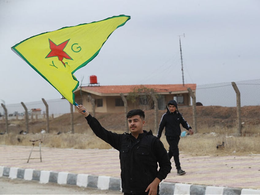 A Syrian Kurd waves the flag of YPG (People's Protection Units) near Qamishli's airport in