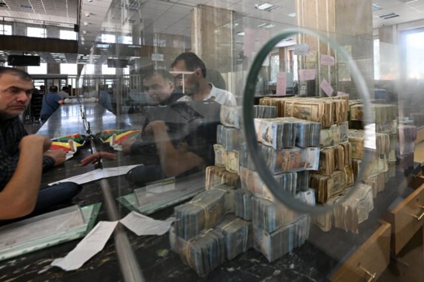 Bank notes of the local currency are piled up as people wait at the central bank in Damasc