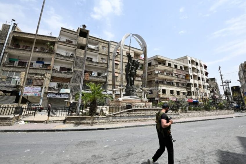 An armed man walks through the mostly Druze and Christian Damascus suburb of Jaramana, whi