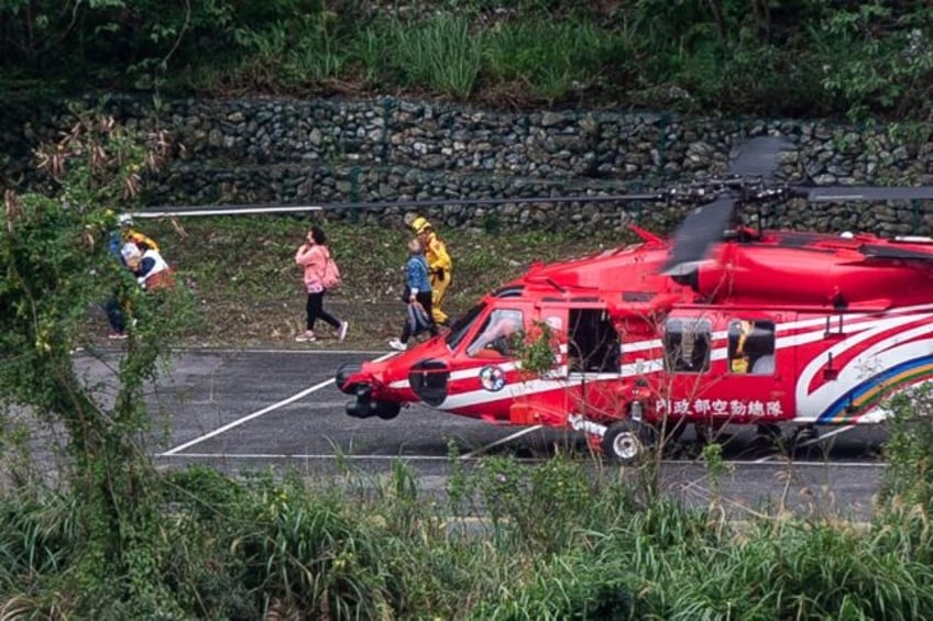 People leave a helicopter after being plucked to safety by rescue personnel from the Natio