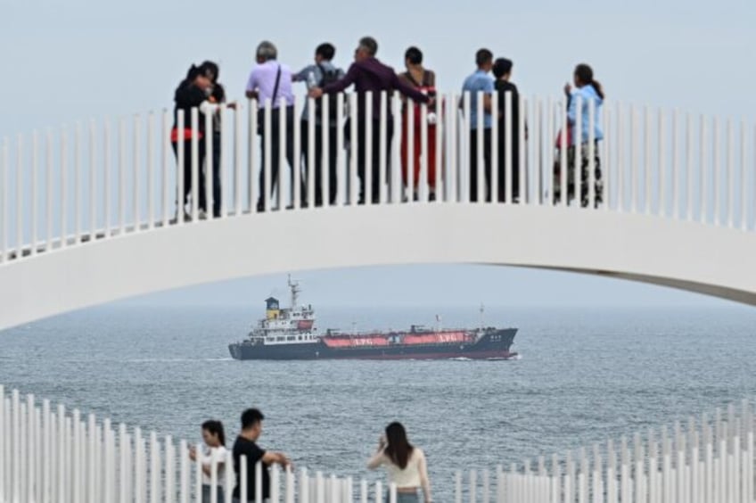 People visit a scenic spot called 68 Nautical Miles as a cargo ship sails past Pingtan isl