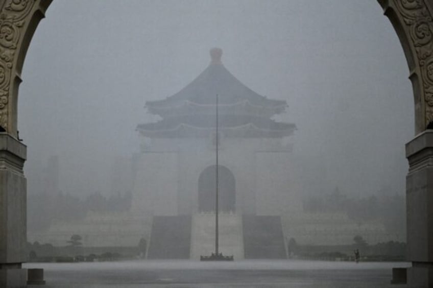 A visitor takes photographs in front of the Chiang Kai-shek Memorial Hall in heavy rain ca