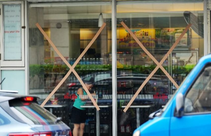 A young boy eats noodles behind store windows in Taiwan taped up in anticipation of the ap