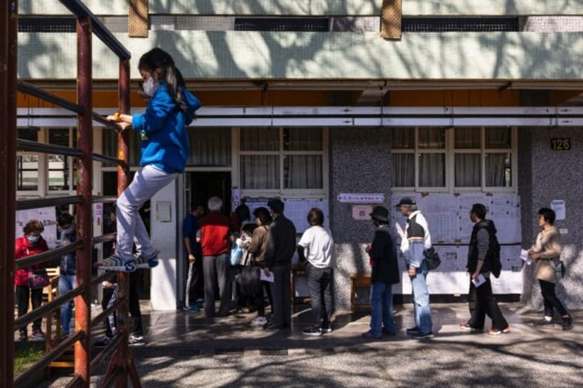 A child plays as people wait to cast their ballots in Taiwan's presidential election at an elementary school in New Taipei City