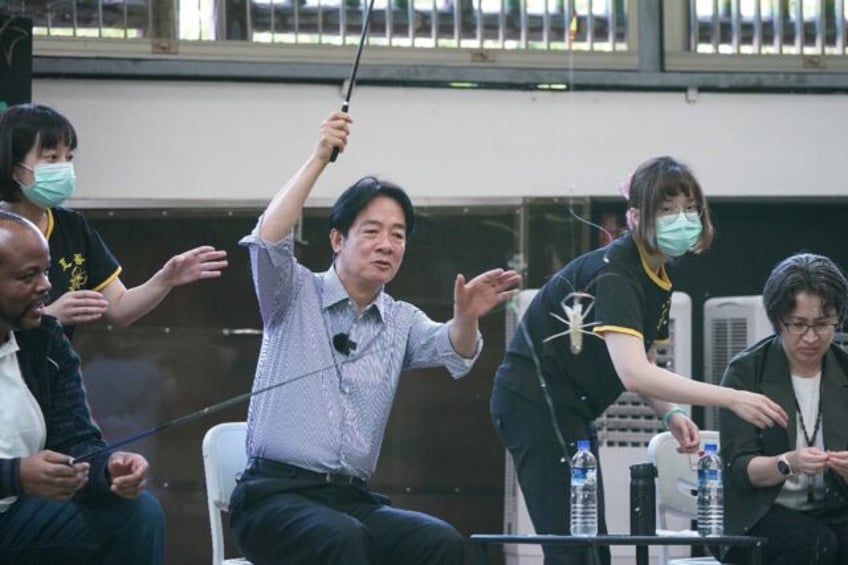 Taiwan's President-elect Lai Ching-te (C) catches a shrimp next to King Mswati III of Eswa