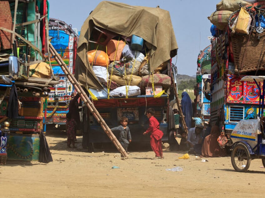 Afghan refugee children play next to trucks loaded with their family's belongings as