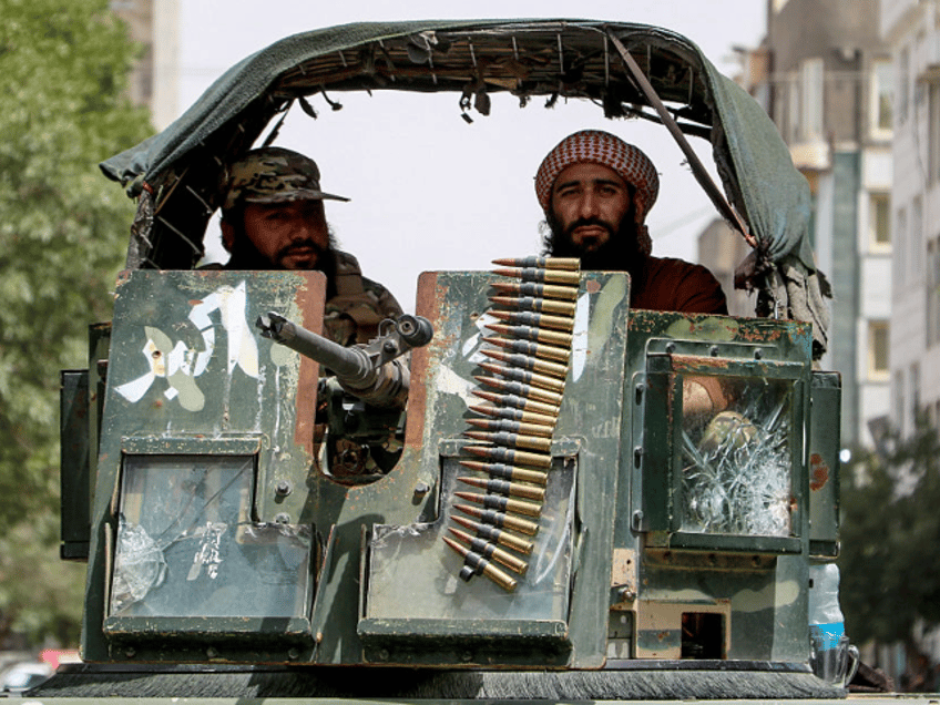 Armed Taliban security personnel sit atop a humvee armored vehicle as they keep guard duri
