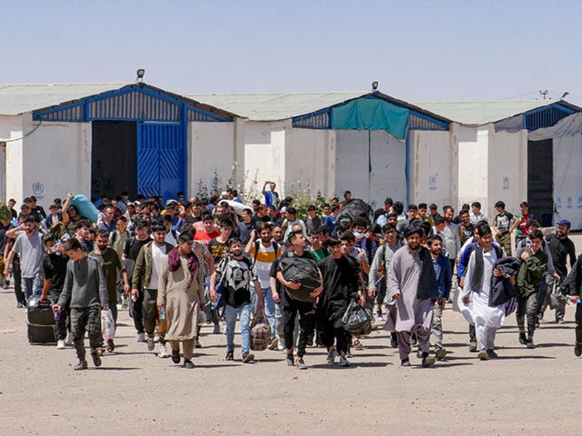 Afghan refugees walk with their belongings after deporting back from Iran at the Islam Qal