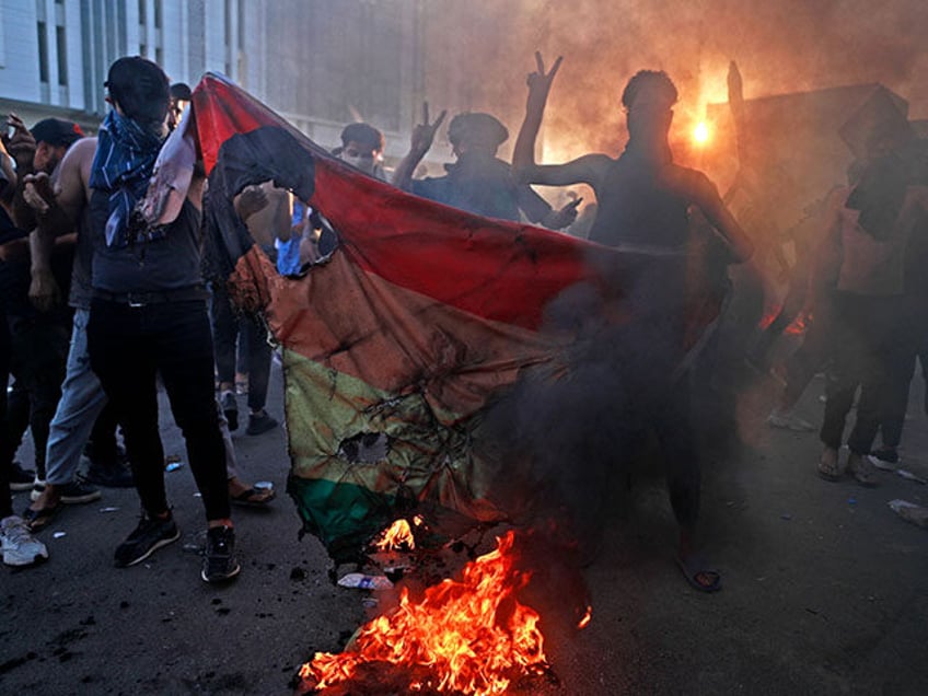 Supporters of Iraq's Sadrist movement burn a rainbow flag outside the Swedish embassy