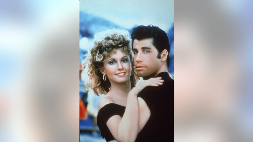 Olivia Newton-John and John Travolta wearing matching black outfits and embracing