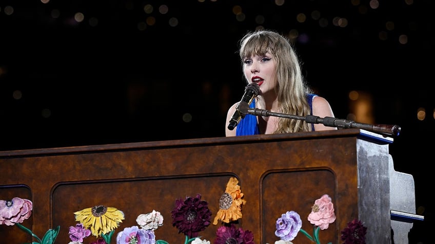 Taylor Swift playing piano in a blue dress