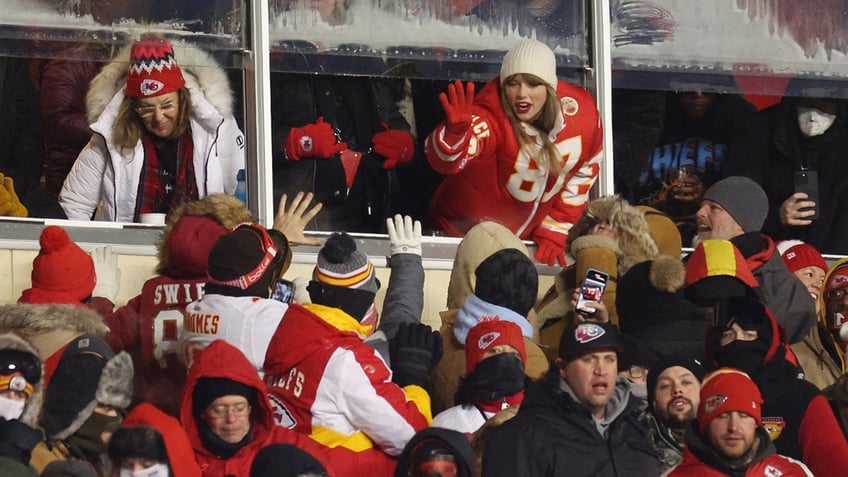 Taylor Swift reaching to high five fans in the crowd