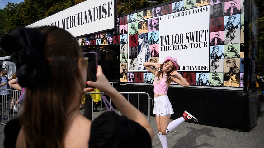 A girl poses in front of a Taylor Swift concert sign in Warsaw