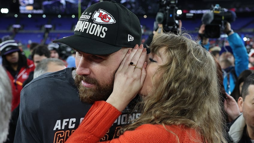 Taylor Swift in a red sweater whispers into Travis Kelce's ear on the football field after the Kansas City Chiefs won the AFC Championship