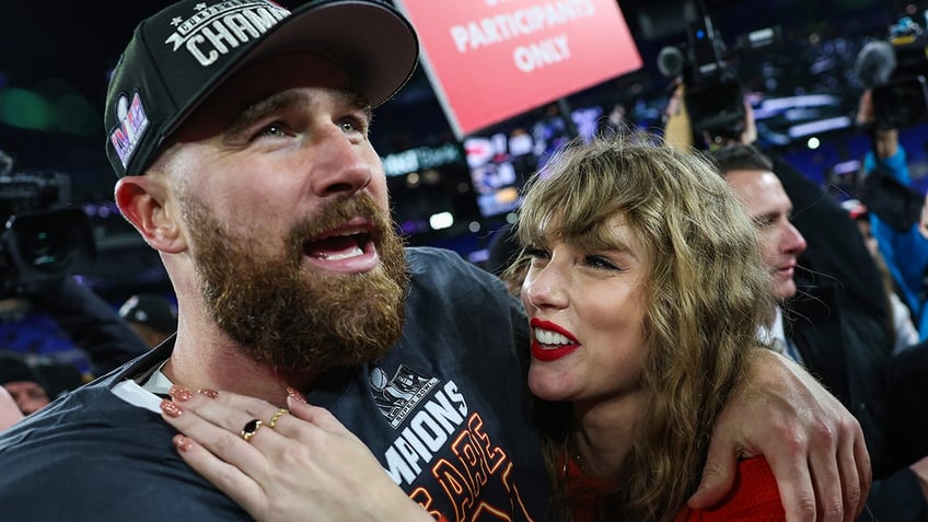 Taylor Swift puts her hand on Travis Kelce's upper chest while she walks on the field with him after the AFC Championship game