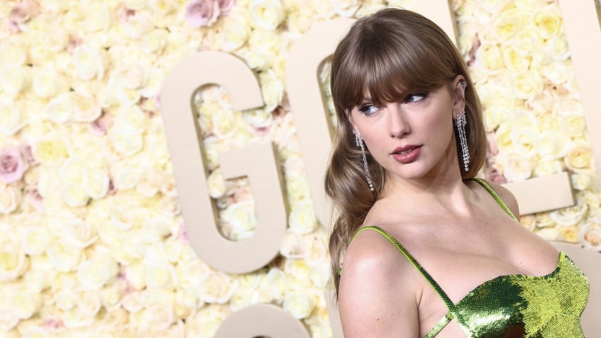 Taylor Swift in a green sequin dress looks over her shoulder